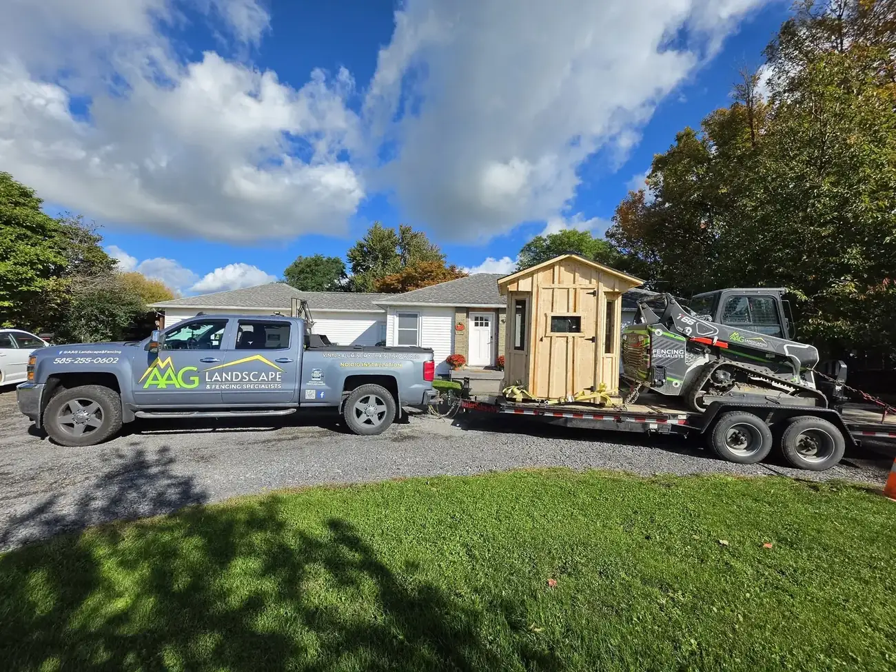 AAG truck and trailer delivering a wooden shed with a compact track loader